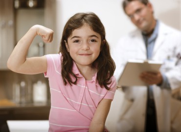 Little girl flexing arm at doctor's office