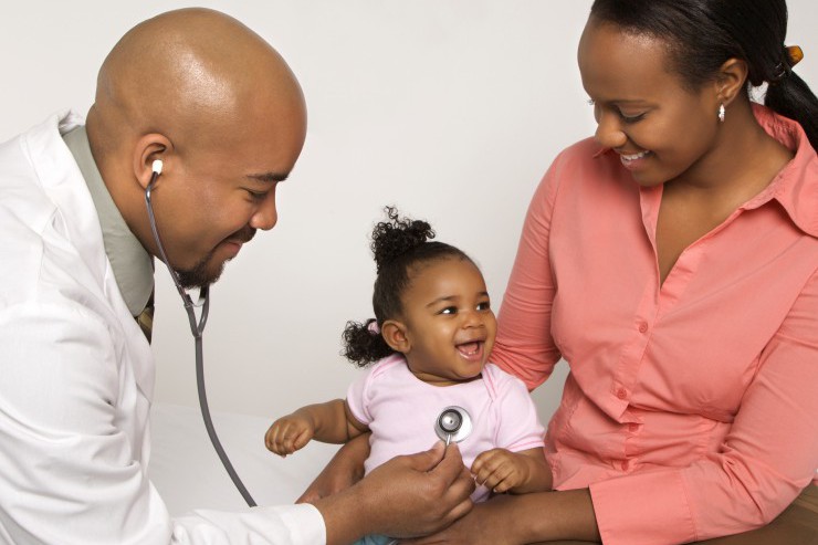 Mother holding baby for pediatrician to examine.